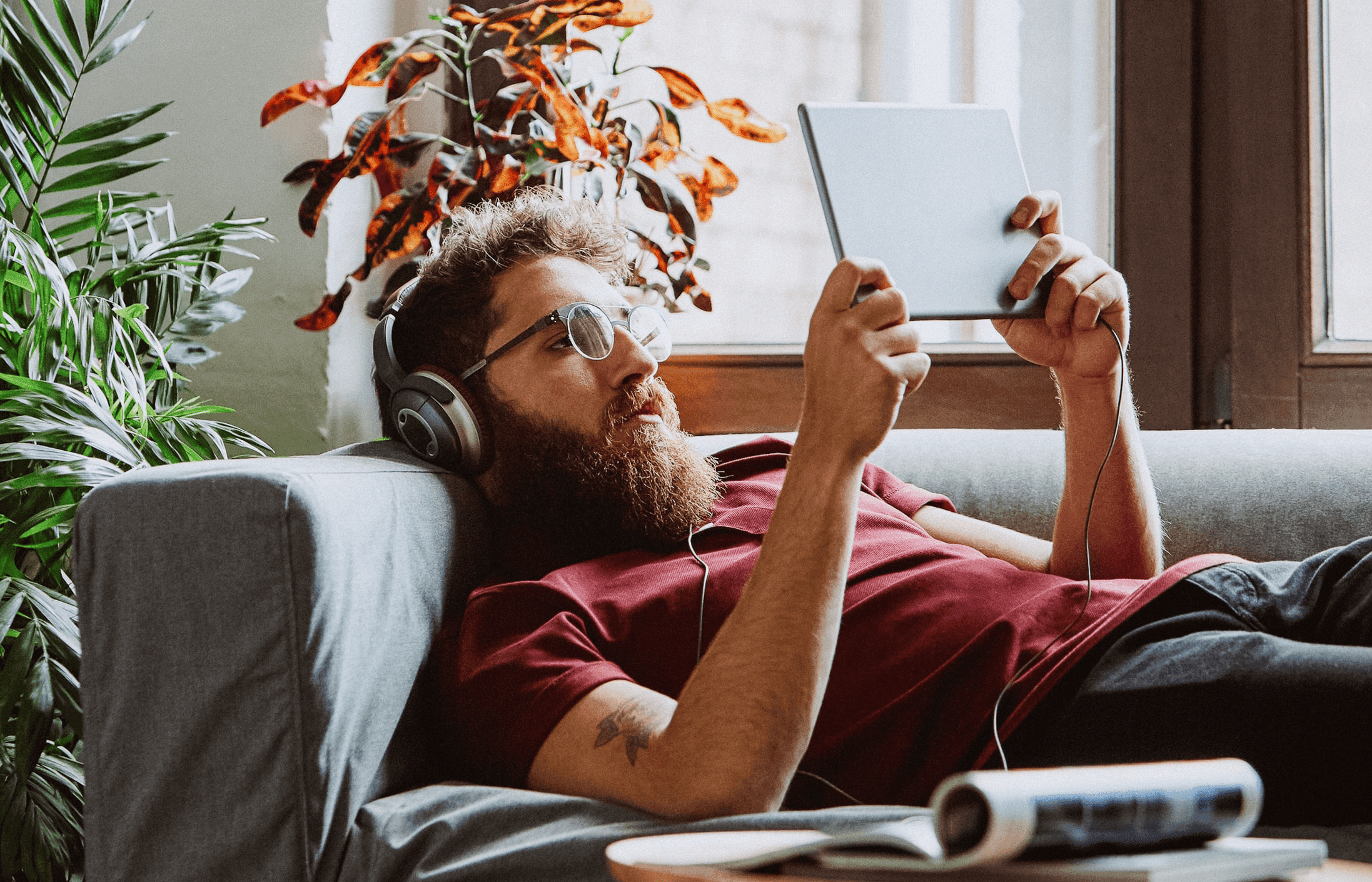 Person on couch with headphones watching video with tablet computer